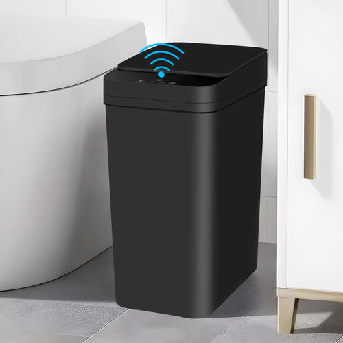 A modern black 12L motion sensor touchless trash can with a blue wireless wave icon on the lid, placed next to a white toilet and vanity cabinet in a bathroom.