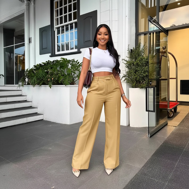 Woman in a white top and beige pants standing in front of a building entrance.