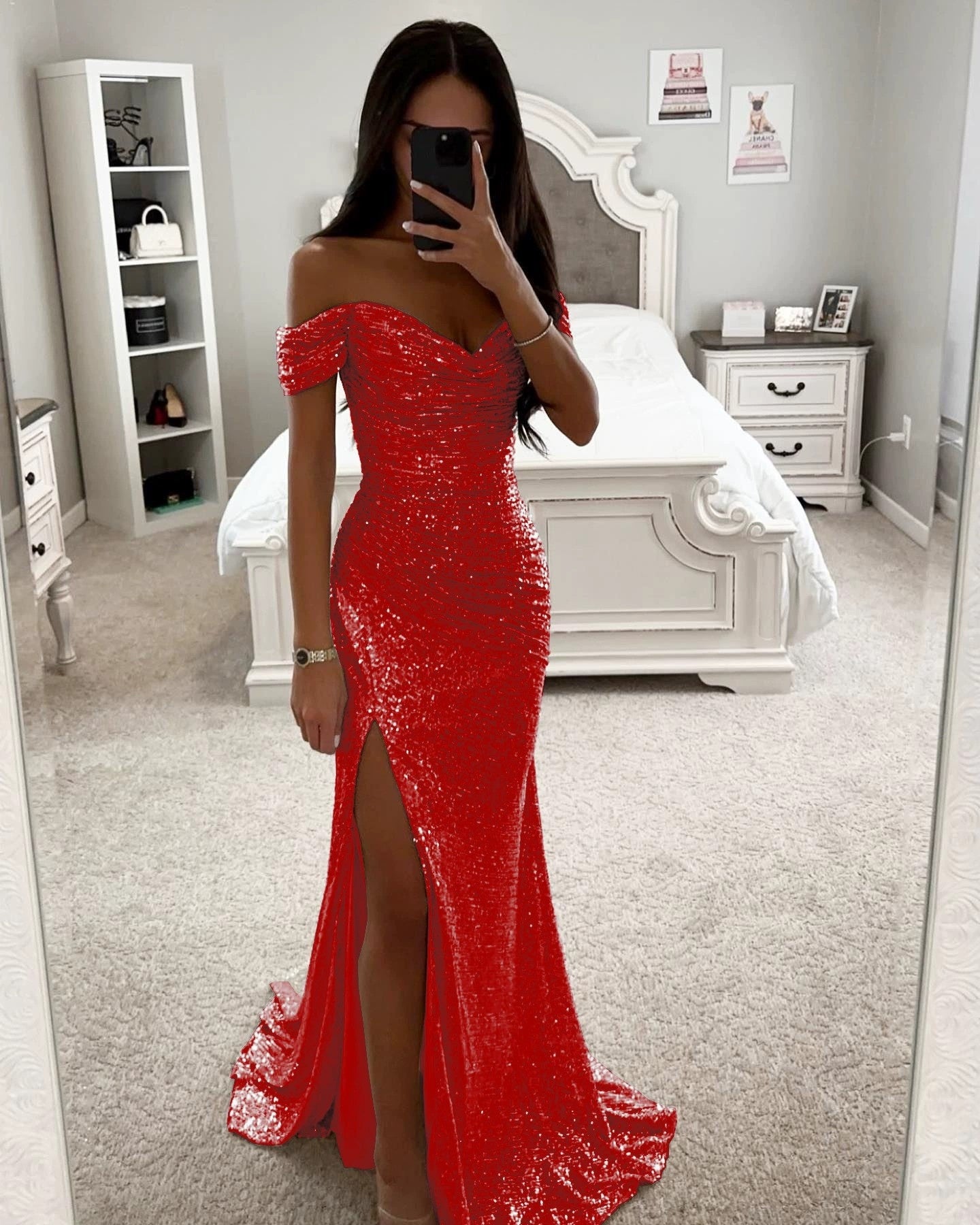 Woman in a red off-shoulder dress standing in a bedroom.