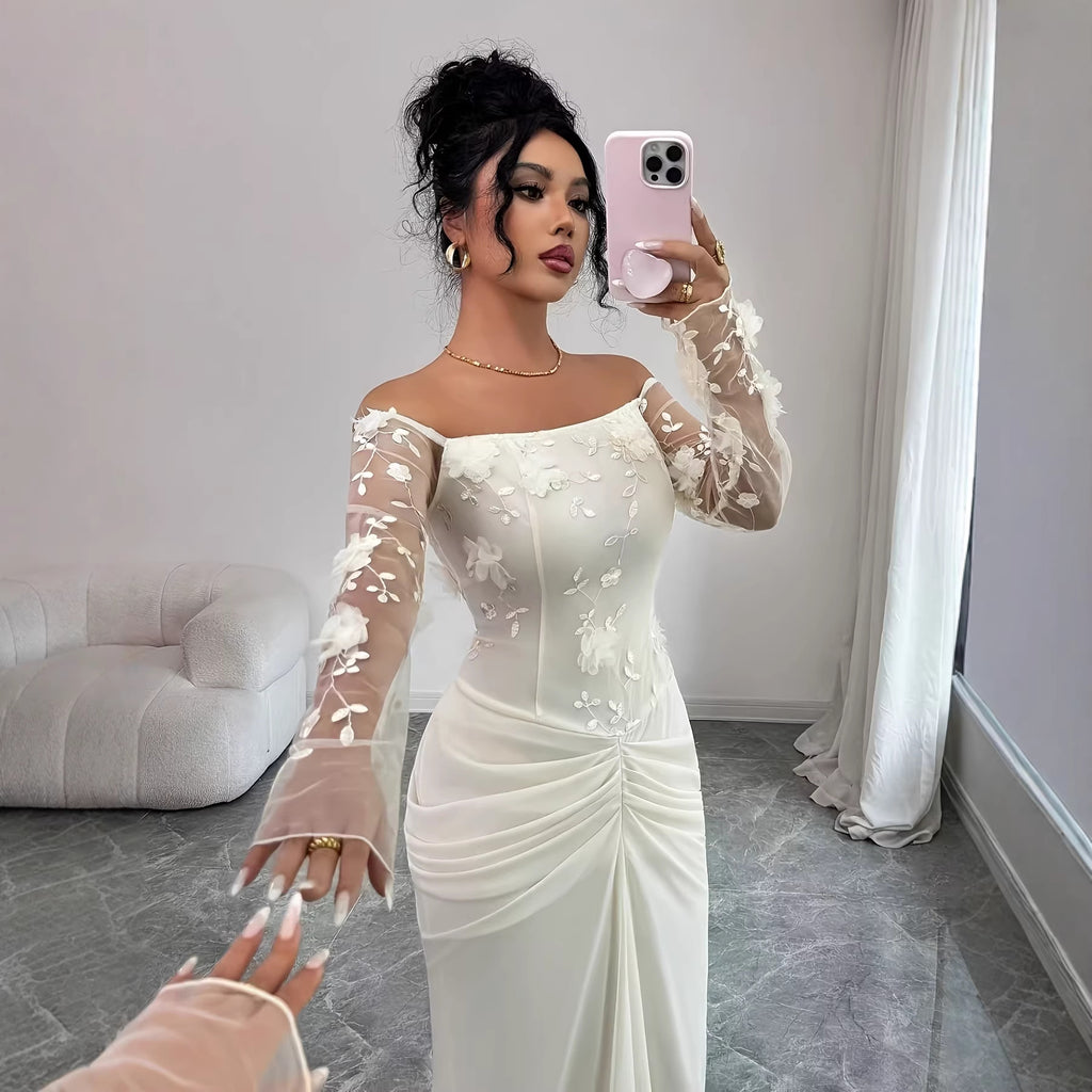 A woman takes a mirror selfie wearing an off-the-shoulder off-white/cream long-sleeve dress with floral lace applique on the sleeves and bodice, gathered ruching at the waist, and a fitted silhouette.