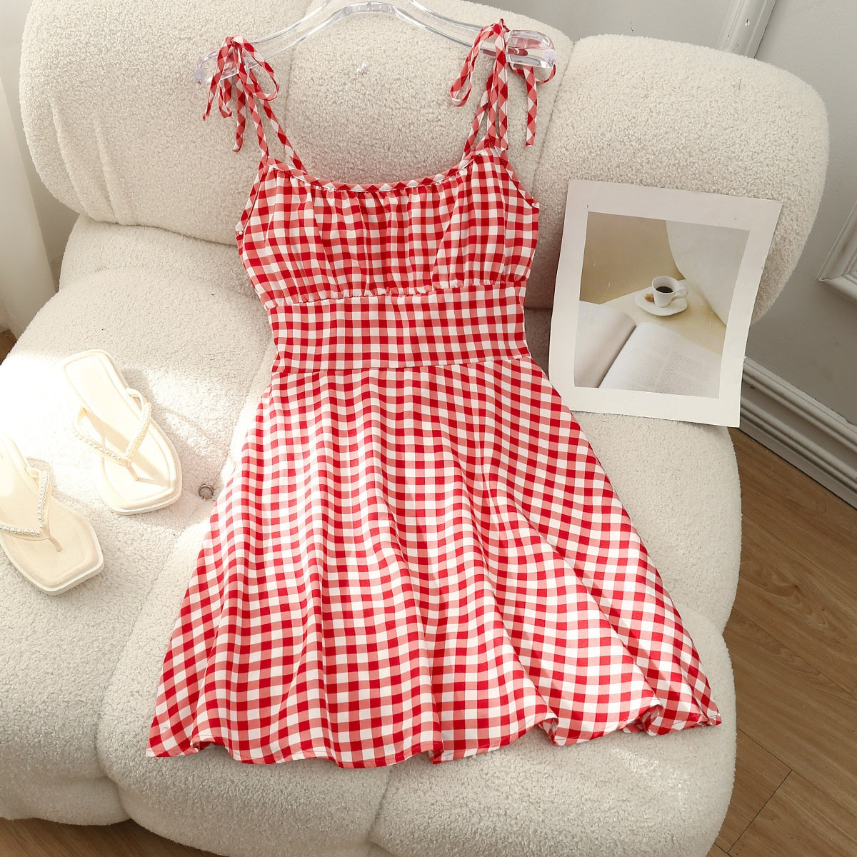 Red and white checkered dress on a hanger against a neutral background