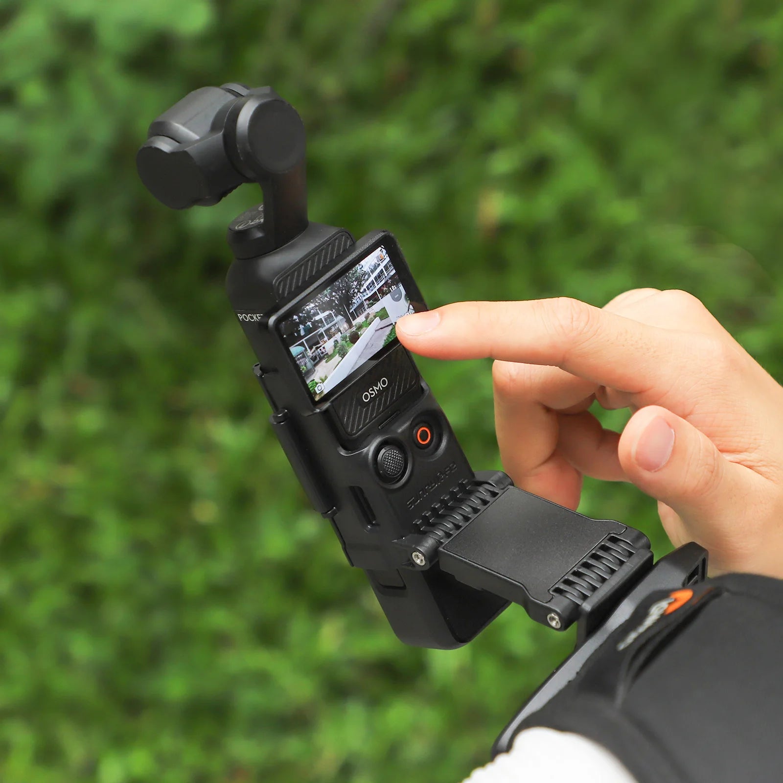 Close-up of a person's hand adjusting a black SUNNYLIFE rotatable backpack clip mount holding a DJI Pocket 3 stabilizer camera.