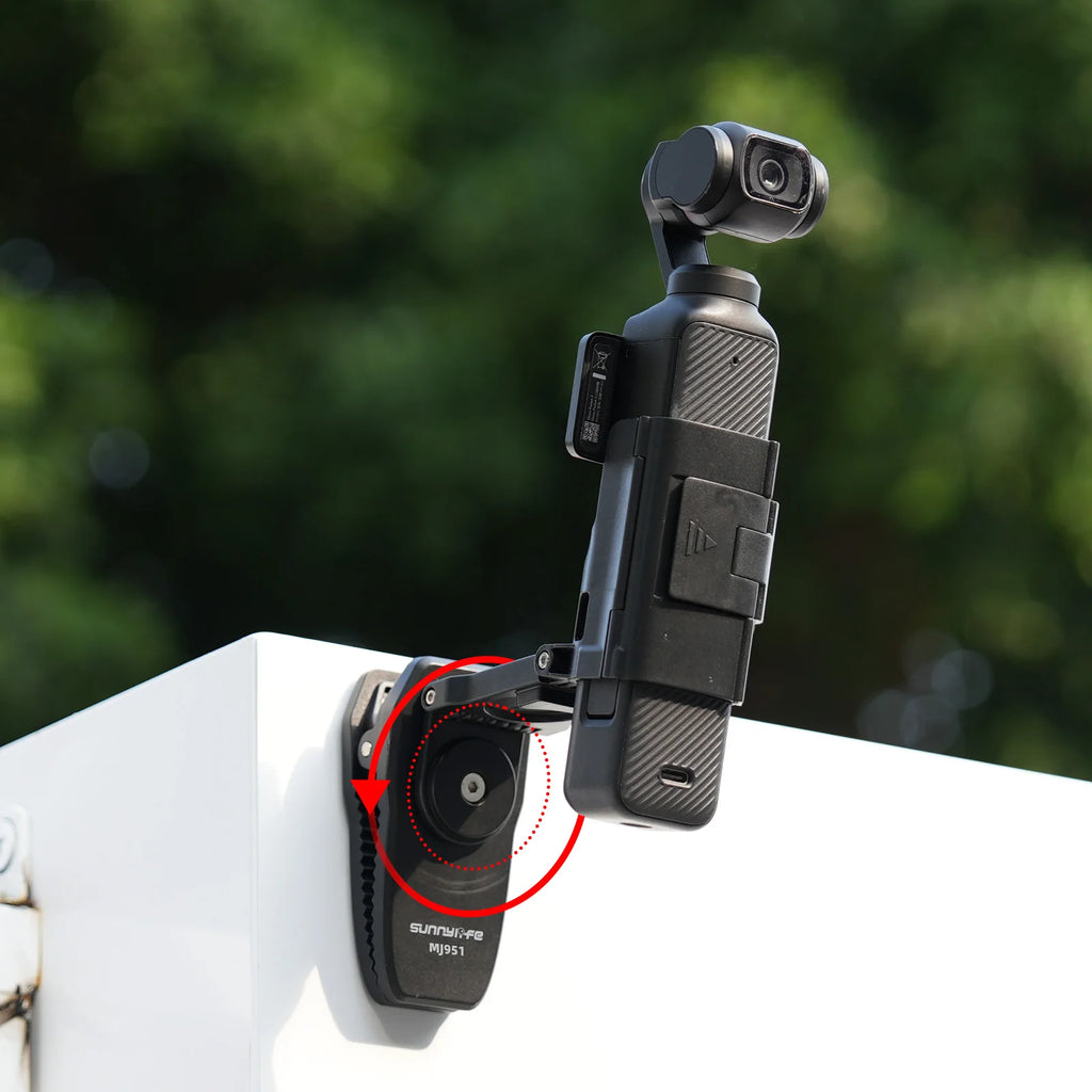 Close-up view of a black SUNNYLIFE backpack clip mount attached to a white surface, demonstrating its 360-degree rotation and adjustable angle design.