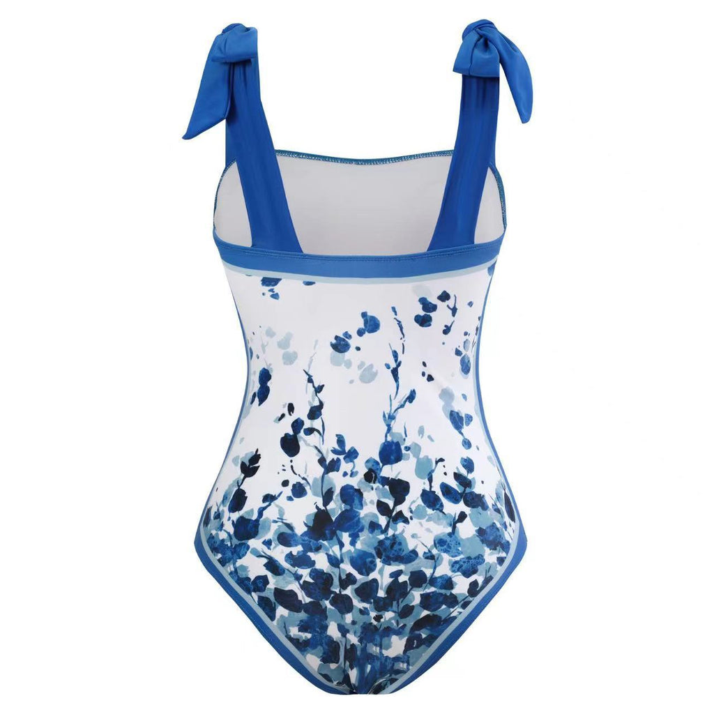 Blue and white floral one-piece swimsuit with bow straps on a white background