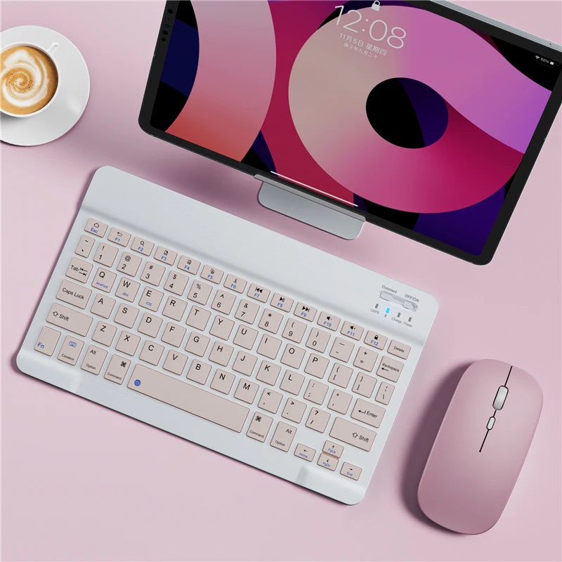 Pink keyboard, mouse, and tablet on a pink surface with a cup of coffee.