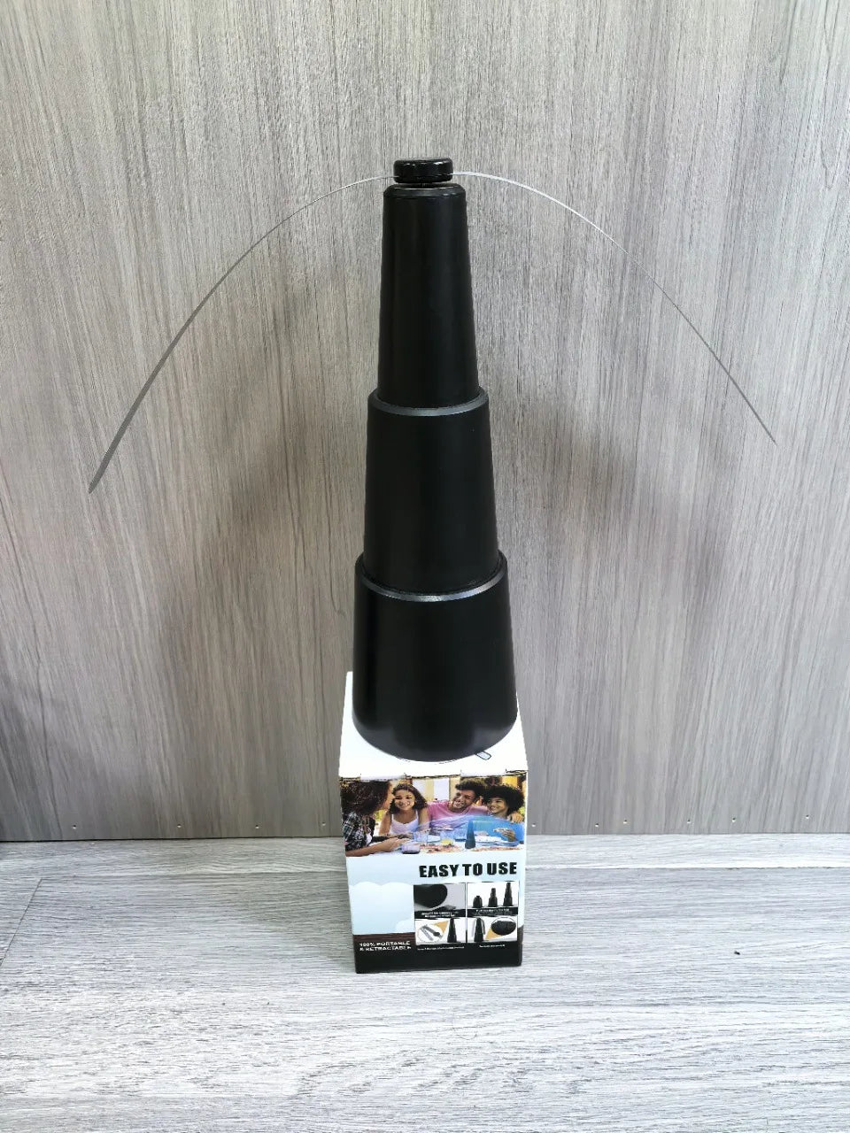 Black adjustable stand on a white box with text against a wooden background
