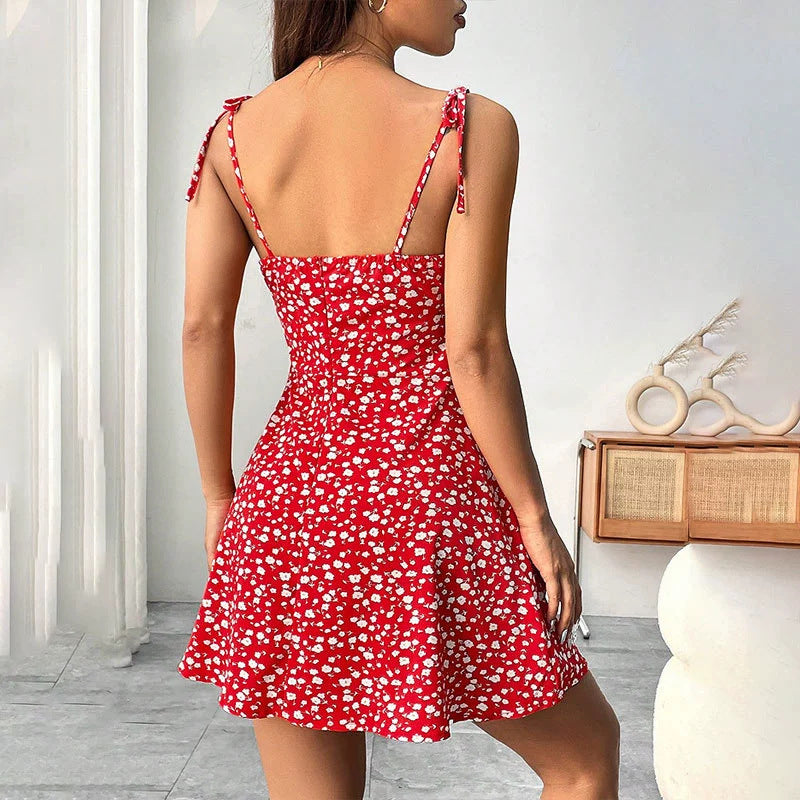 Woman wearing a red floral dress with thin straps in an indoor setting.