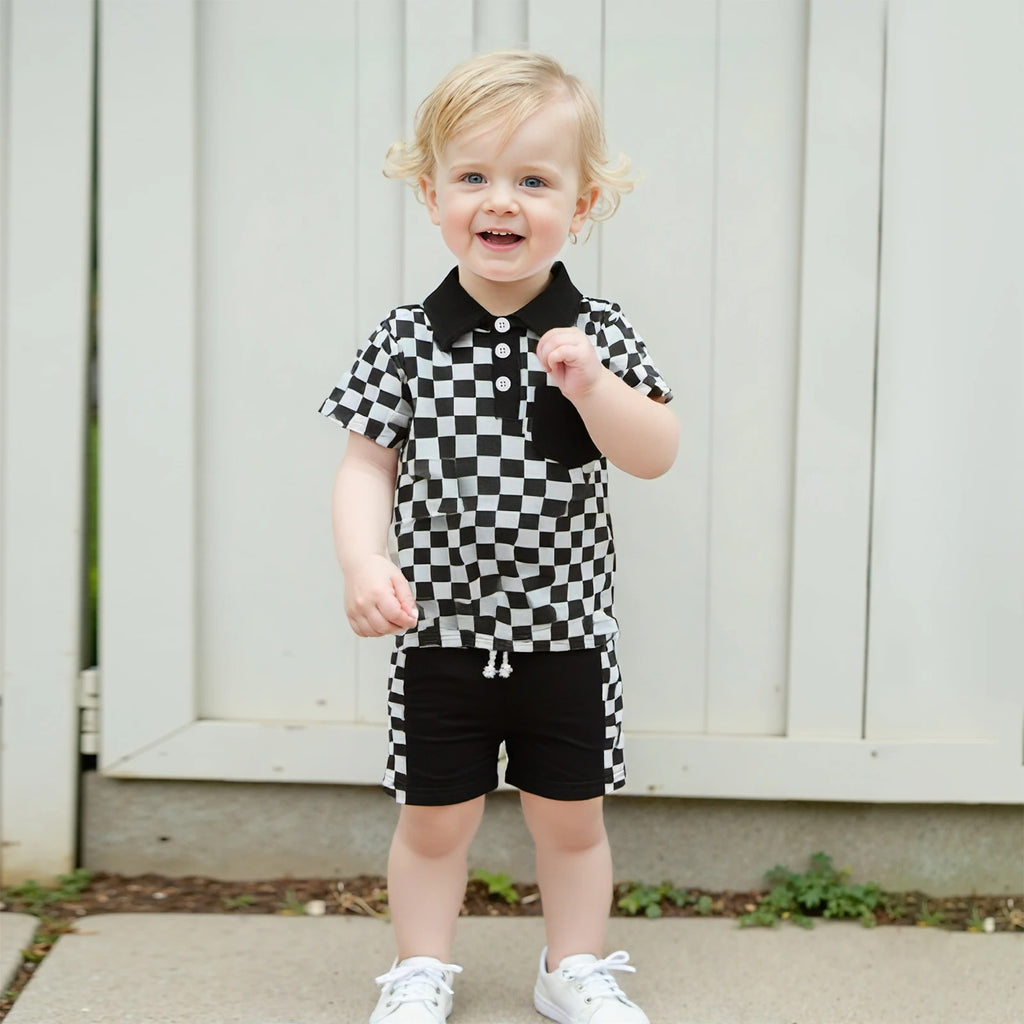 Toddler boy wearing a black checkered lapel shorts set with white sneakers