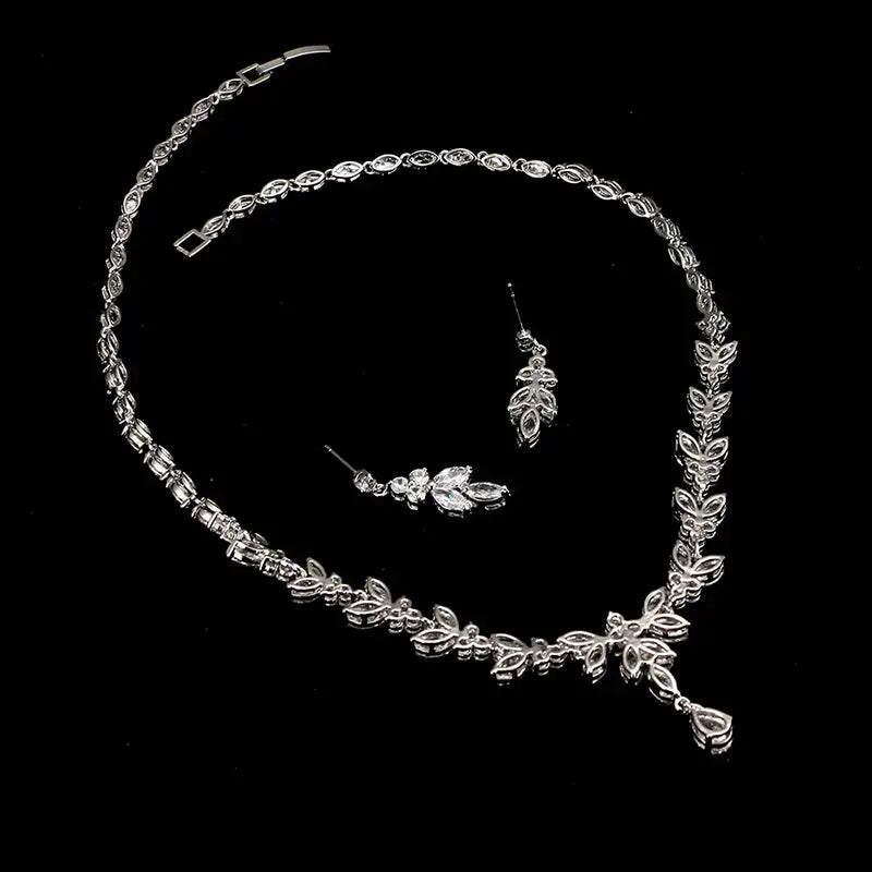 Silver jewelry set including necklace, bracelet, and earrings on a black background