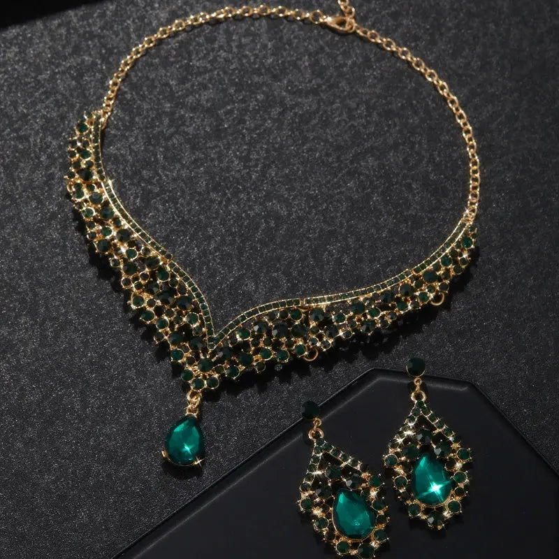 Gold and green gemstone necklace and earrings on a dark surface
