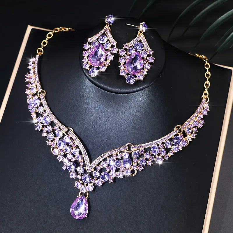 Purple gemstone necklace and earrings on a black stand with gold accents.