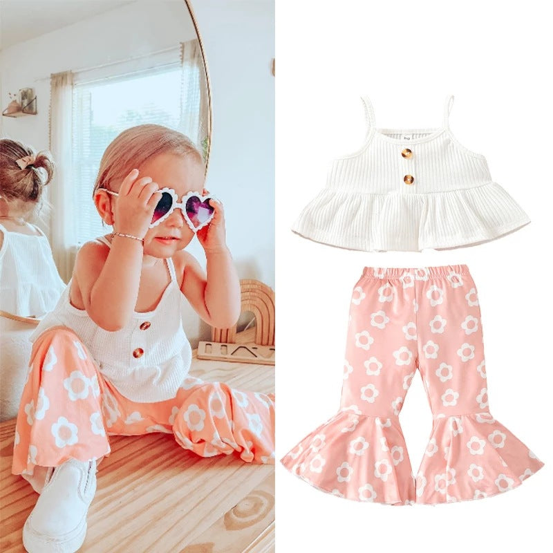 Close-up detail of girls' white cotton spaghetti-strap top and floral trousers