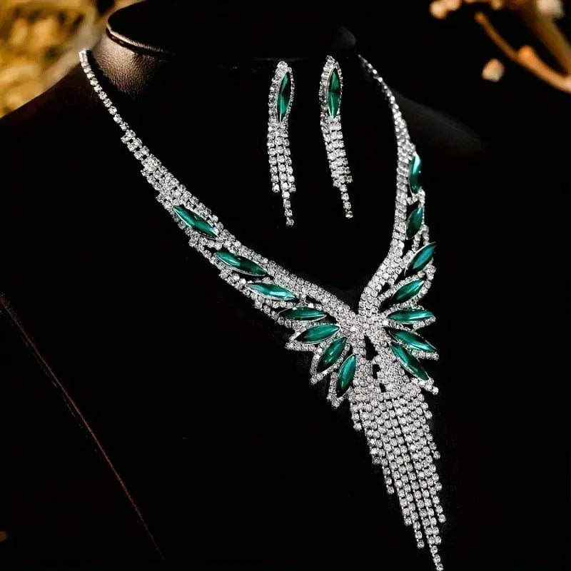Close-up view of the crystal-embellished tassel necklace and earrings, highlighting the emerald-green stone accents and intricate sparkle.